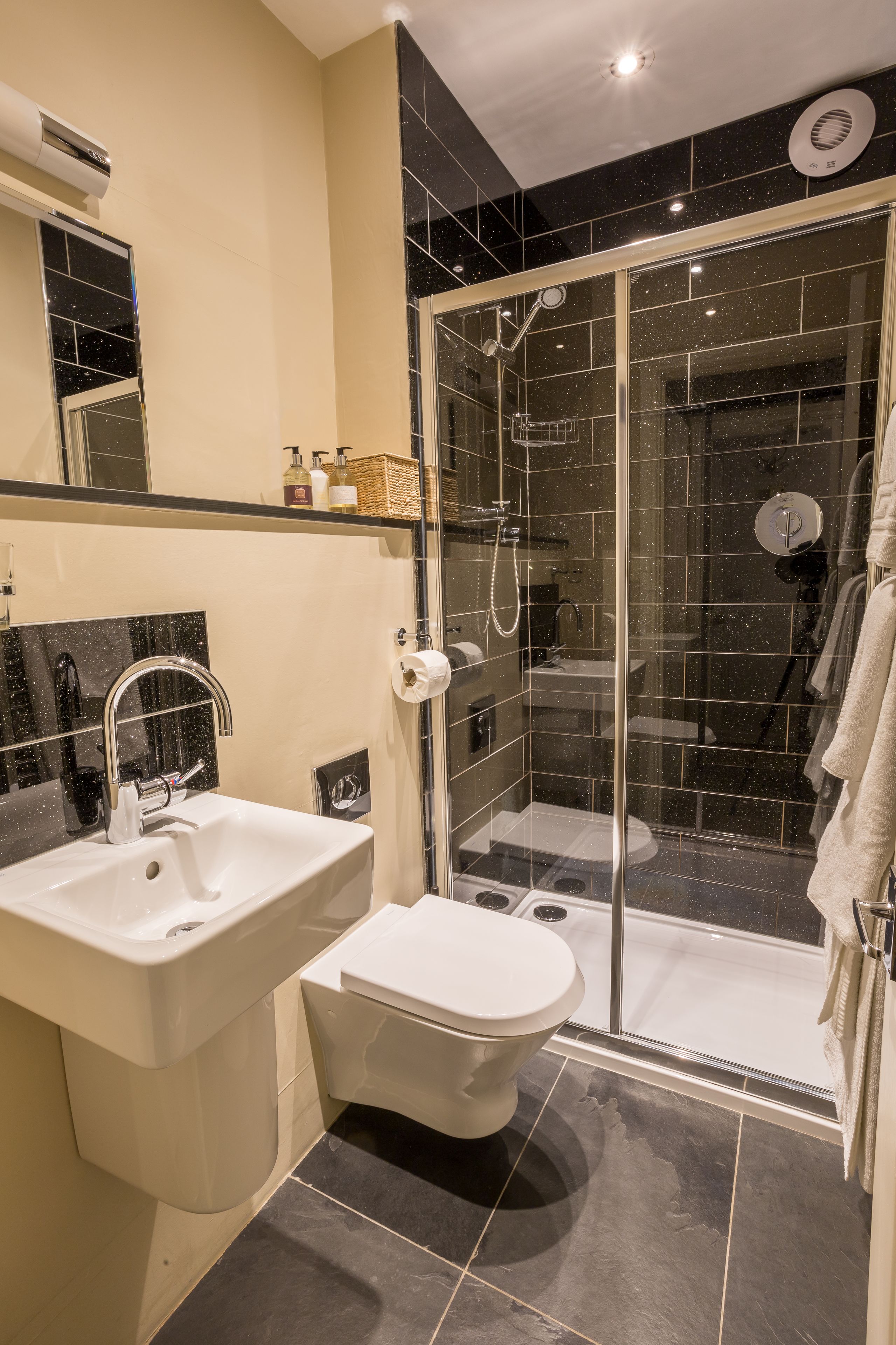 Un baño moderno con ducha de vidrio, lavamanos blanco y retrete.