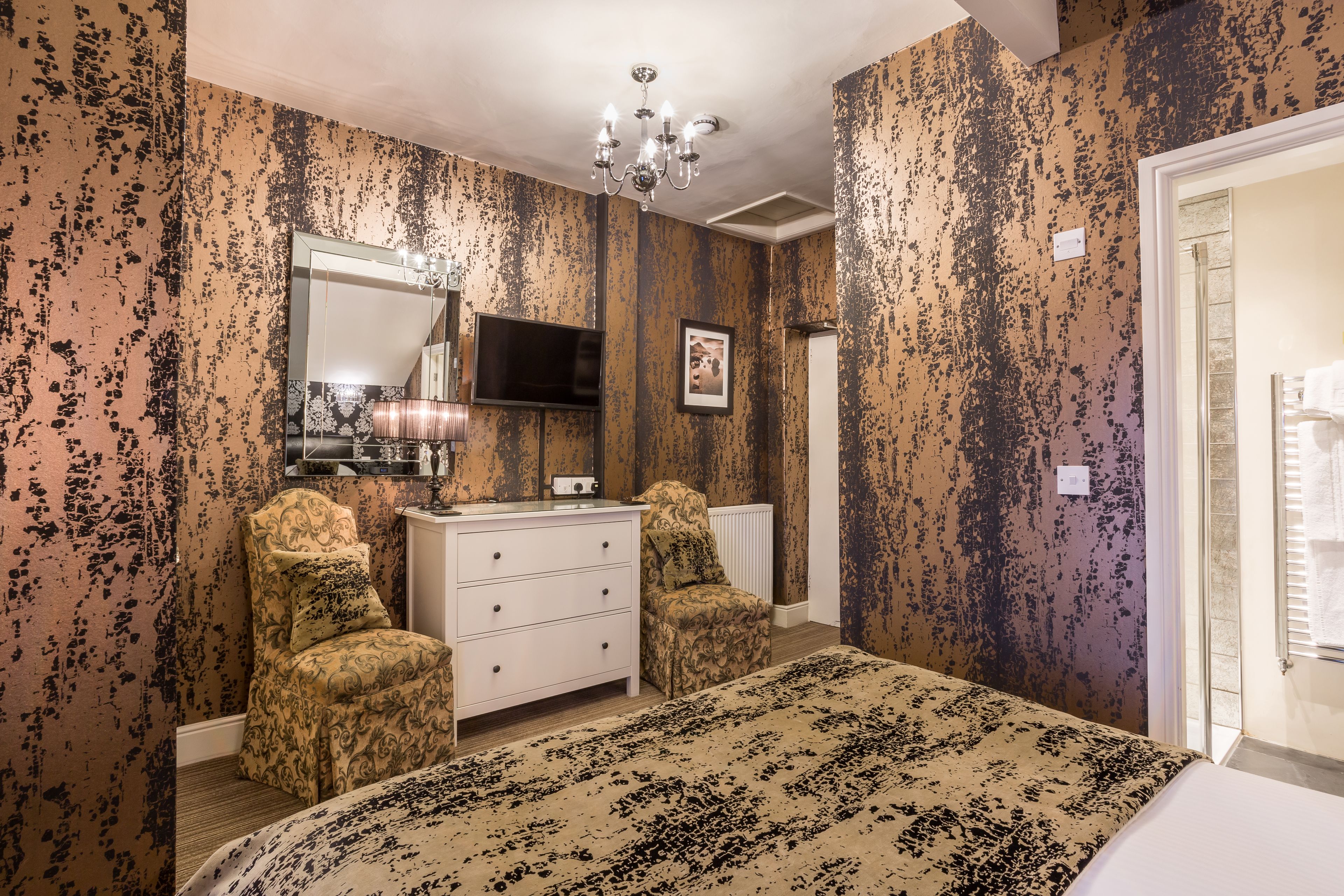 A bedroom with a bed, dresser, chair, and a television.