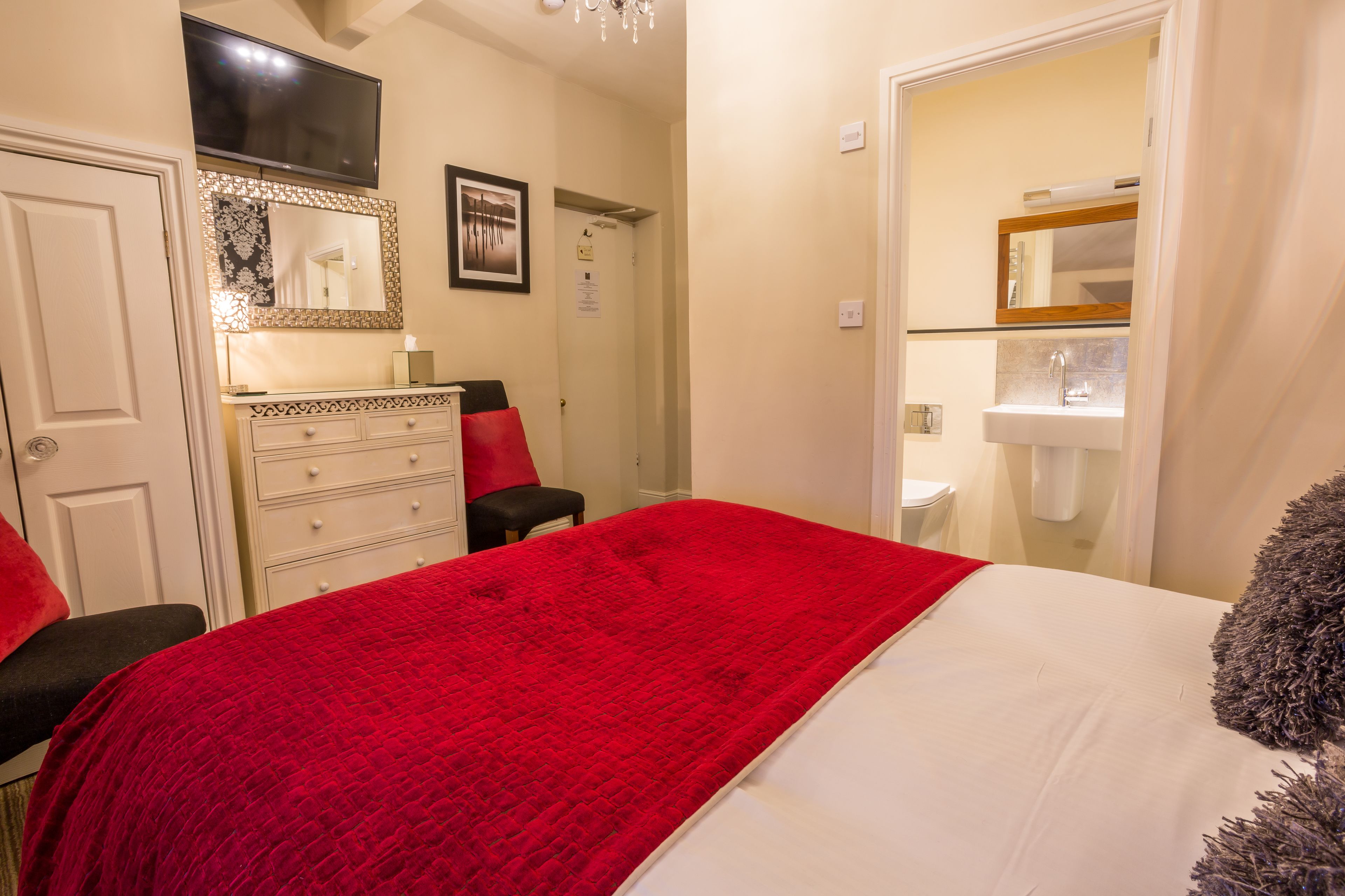 Une chambre à coucher avec un lit, une commode, un miroir et un téléviseur.