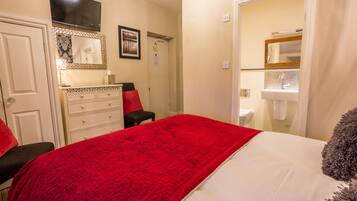 A bedroom with a bed, a dresser, a mirror, and a television.