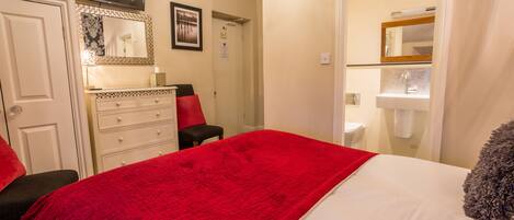 Une chambre à coucher avec un lit, une commode, un miroir et un téléviseur.