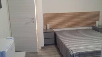 Un dormitorio con cama, mesita de noche, cabecero de madera y una puerta.