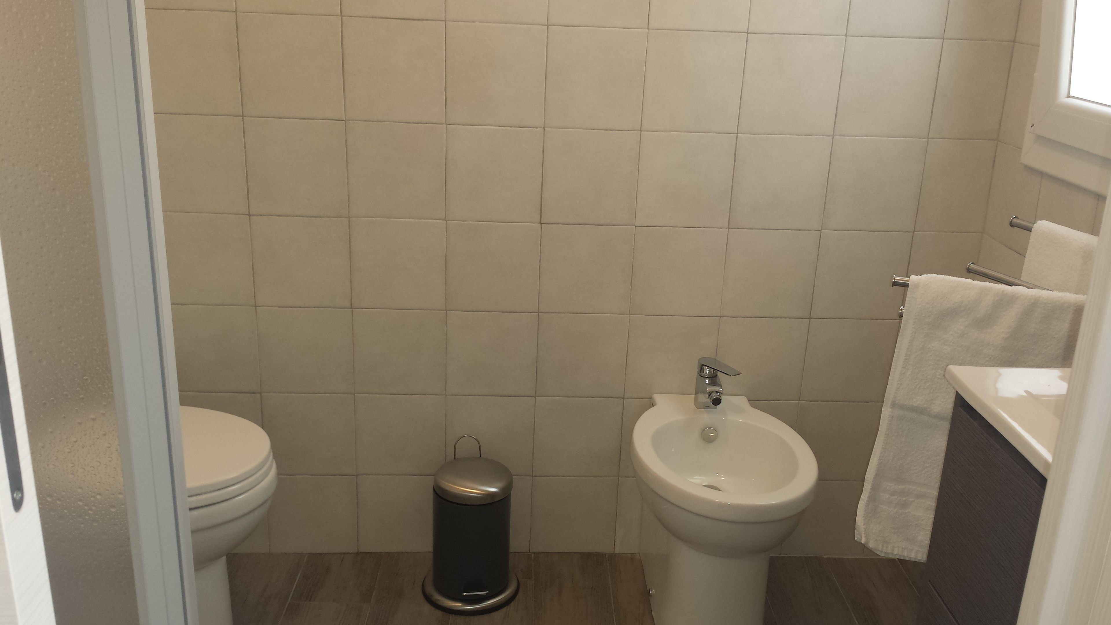 Un baño pequeño y limpio con inodoro, bidé y cubo de basura.