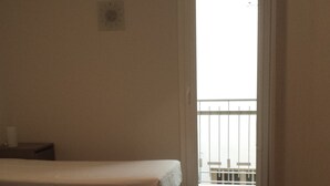 A room with two beds, a table, and a balcony with a railing. - Beda Ragusa (Ragusa)