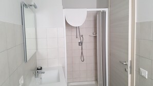 A modern bathroom with a white sink, a mirror, a shower with a glass door, and a toilet. - Beda Ragusa (Ragusa)