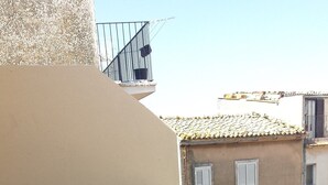 A balcony with tiled flooring, a beige wall, and a metal railing. - Beda Ragusa (Ragusa)