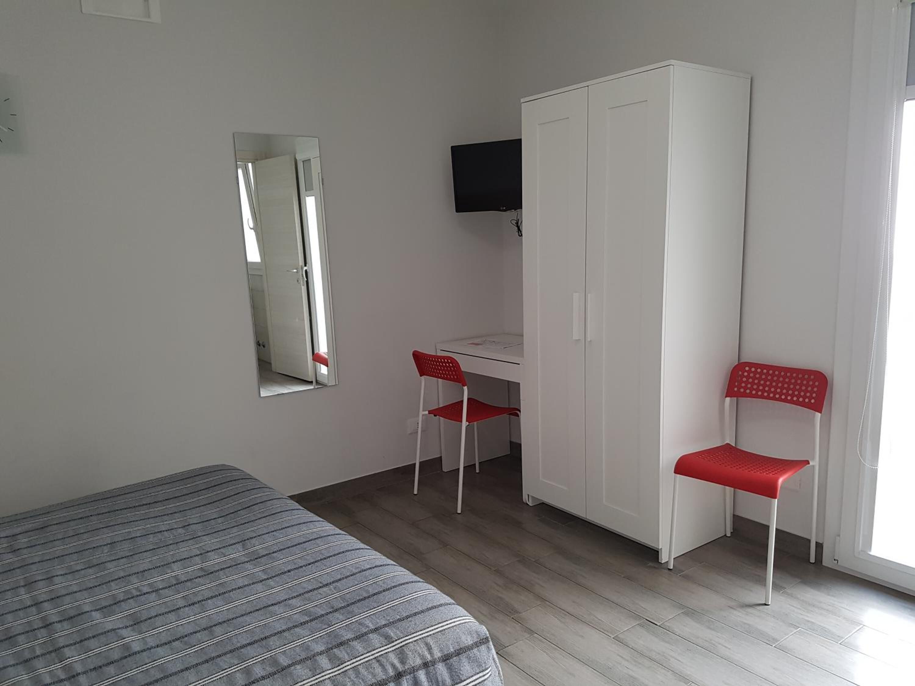 Ein Zimmer mit einem Bett, einem Schreibtisch, einem Kleiderschrank und einem Stuhl.