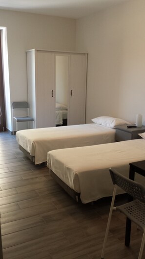 A hotel room with two single beds, a wardrobe, a chair, and a bedside table. - Beda Ragusa (Ragusa)