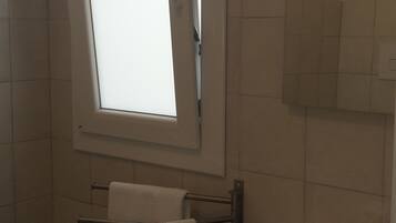 Un baño con ventana, lavabo y toallero.