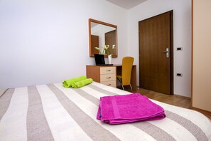 A bedroom with a bed, a desk, a chair, a mirror, and a wardrobe. - Apartments Davorka (Rovinj)