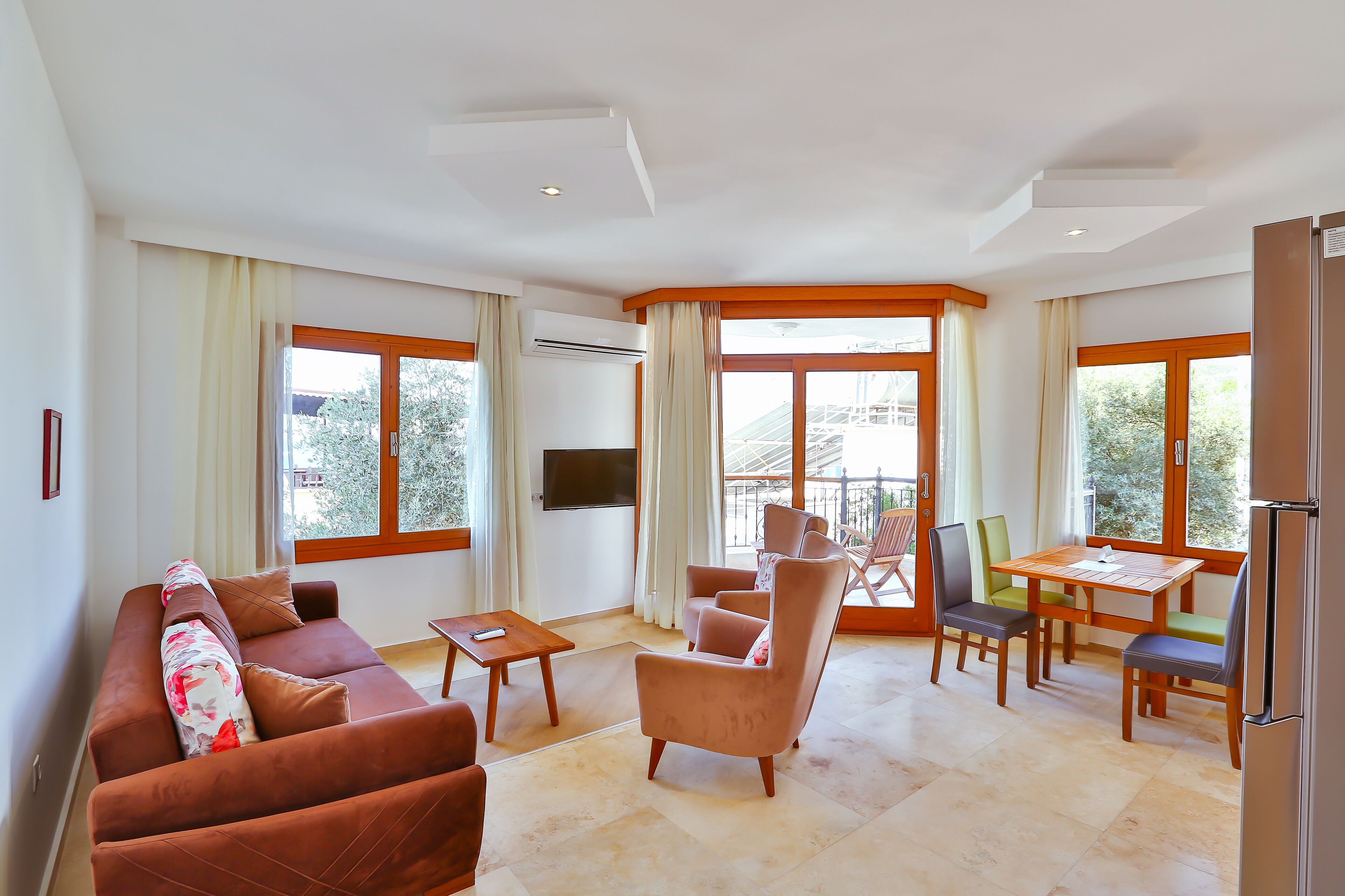 A modern living room with a sofa, armchairs, a coffee table, and a dining area with chairs and a table.