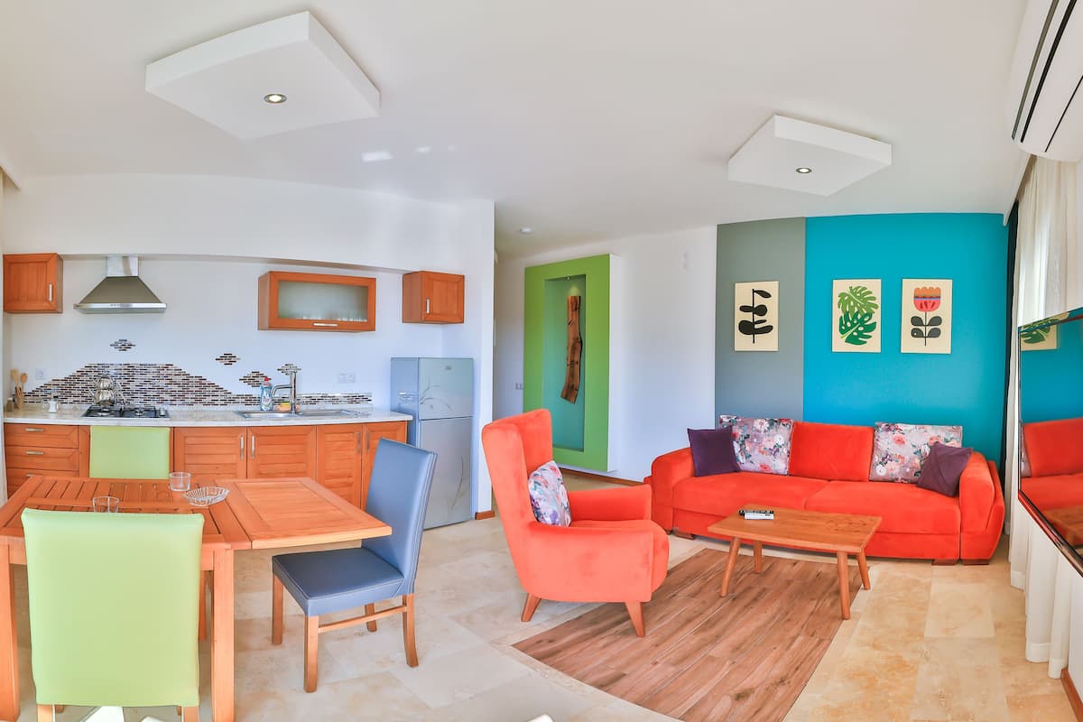 A modern living space with a kitchen, dining area, and a living room with a sofa and chairs.