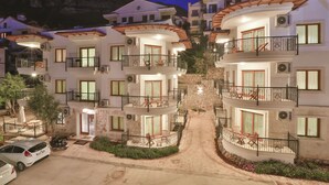 A multi-story hotel with balconies, a stone facade, and a paved driveway. - Cinarlar Apart Hotel (Kas)