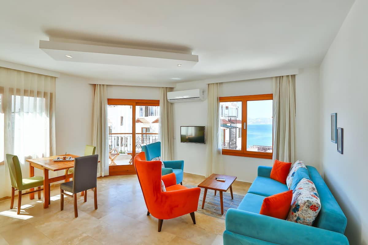 A spacious living room with a wooden table, two chairs, a sofa, and a TV.