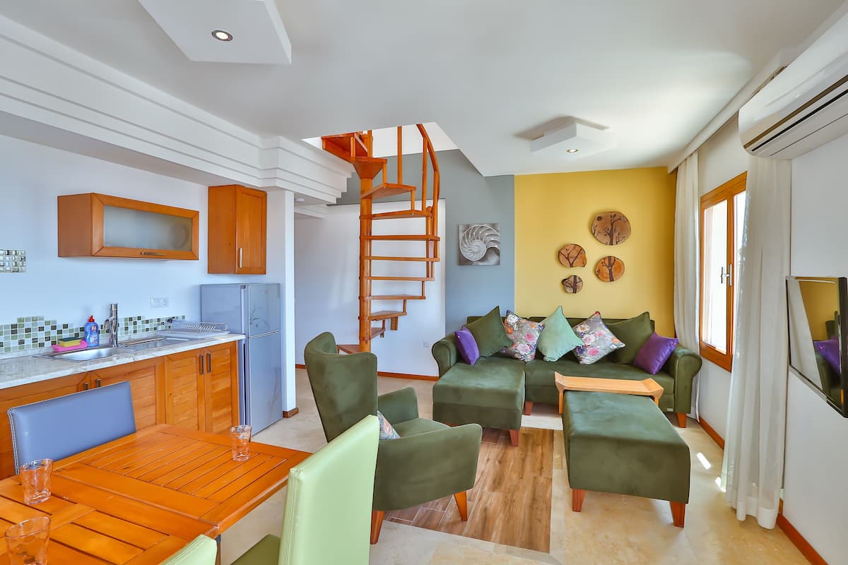 A compact living space with a kitchen, dining area, and a cozy seating area with a spiral staircase.