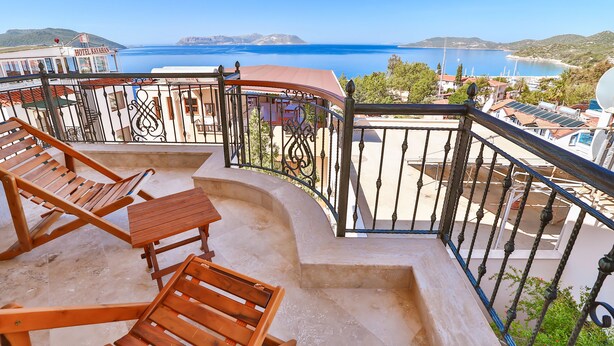 A balcony with wooden furniture, a view of the sea, and a building labeled "HOTEL KARAMAN". - Cinarlar Apart Hotel (Kas)