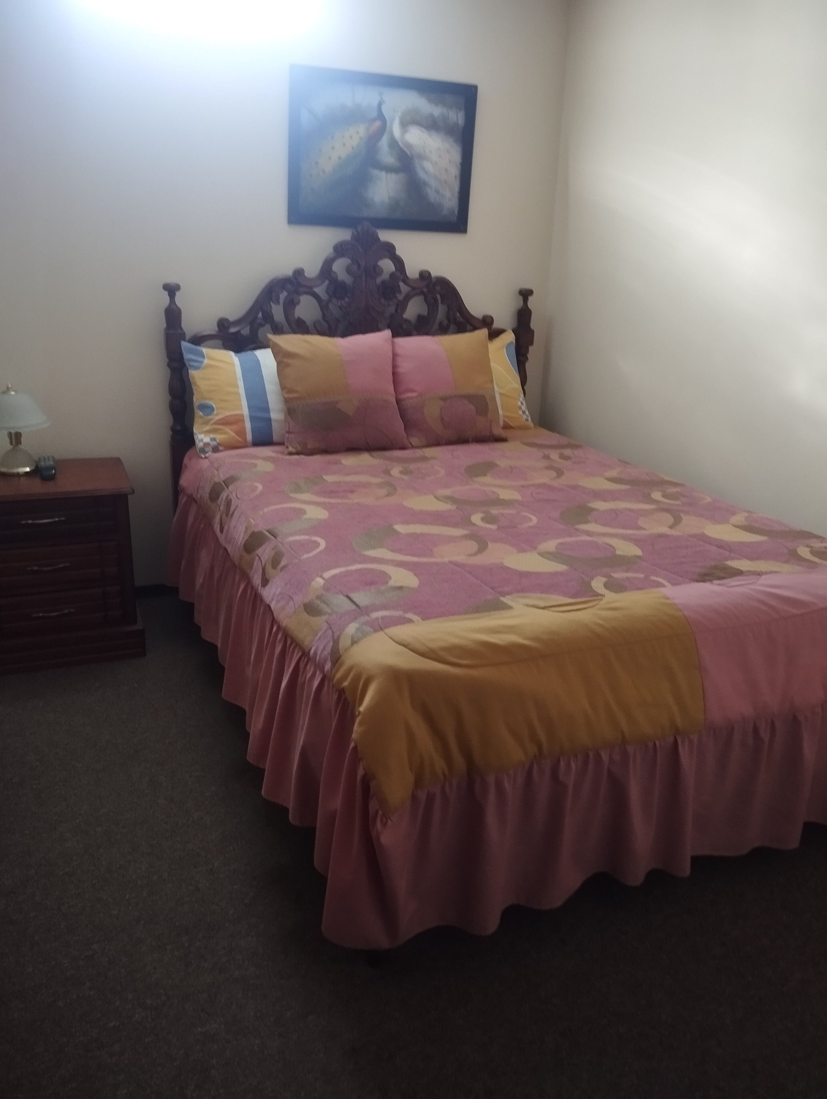 Un dormitorio con una cama de madera, una mesita de noche y un cuadro colgado en la pared.