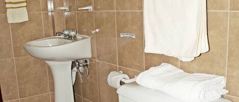 Une salle de bain avec des toilettes blanches, un lavabo et un miroir.