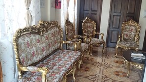 A room with ornate sofas and armchairs, a patterned floor, and a door marked "BANOS". - Hotel Residencial El Viajero (Tababela)