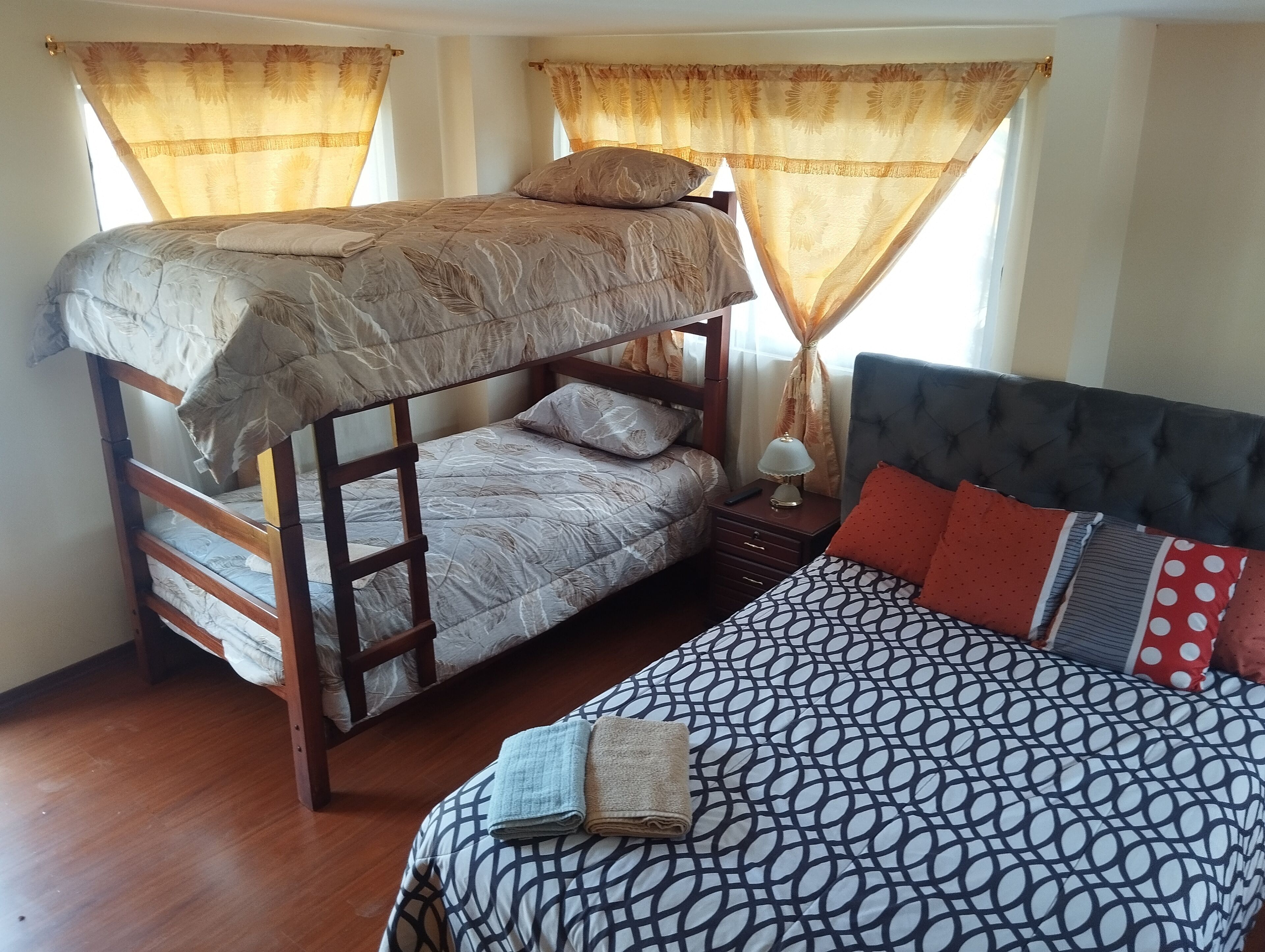 Un dormitorio con una cama individual, una litera y una mesita de noche con lámpara.