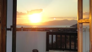 Ein Balkon mit Blick auf den Sonnenuntergang über Meer und Bergen.
