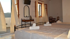 Ein Hotelzimmer mit zwei Betten, einem Fernseher, einem Schreibtisch mit einer Vase und Blick auf die Berge.