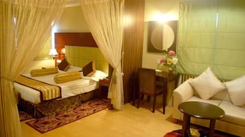 Una habitación de hotel con una cama, un escritorio, una silla, un sofá y una mesita.