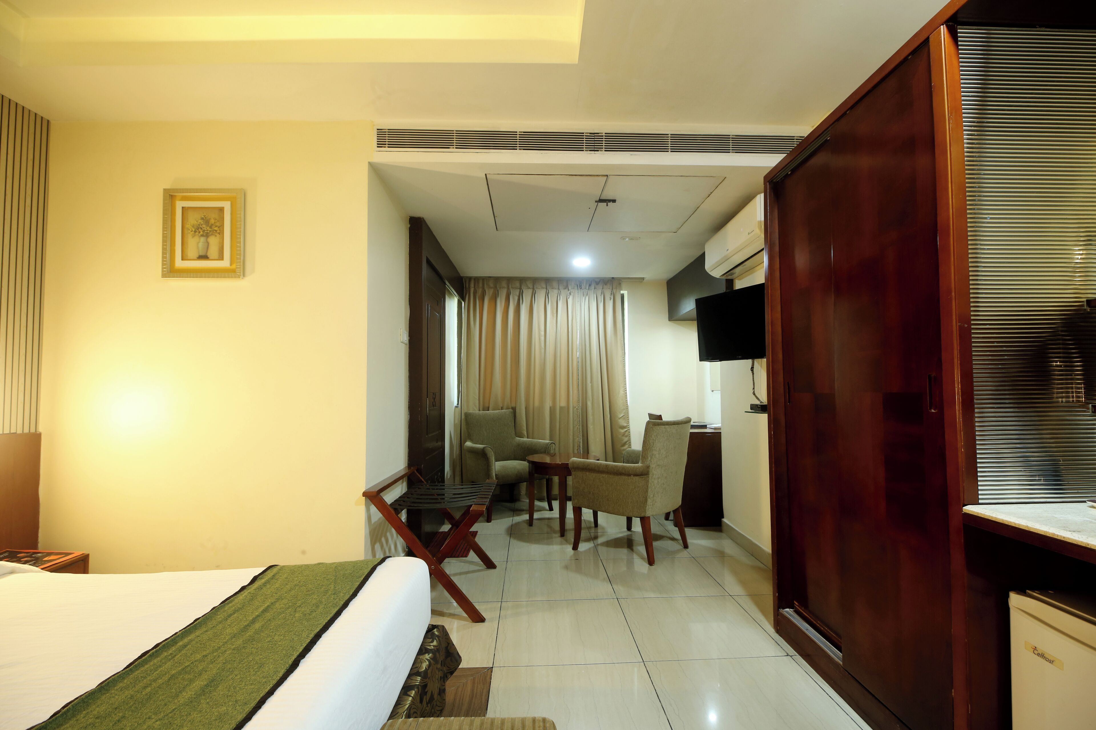 Una habitación de hotel con cama, escritorio, silla, televisor y armario.