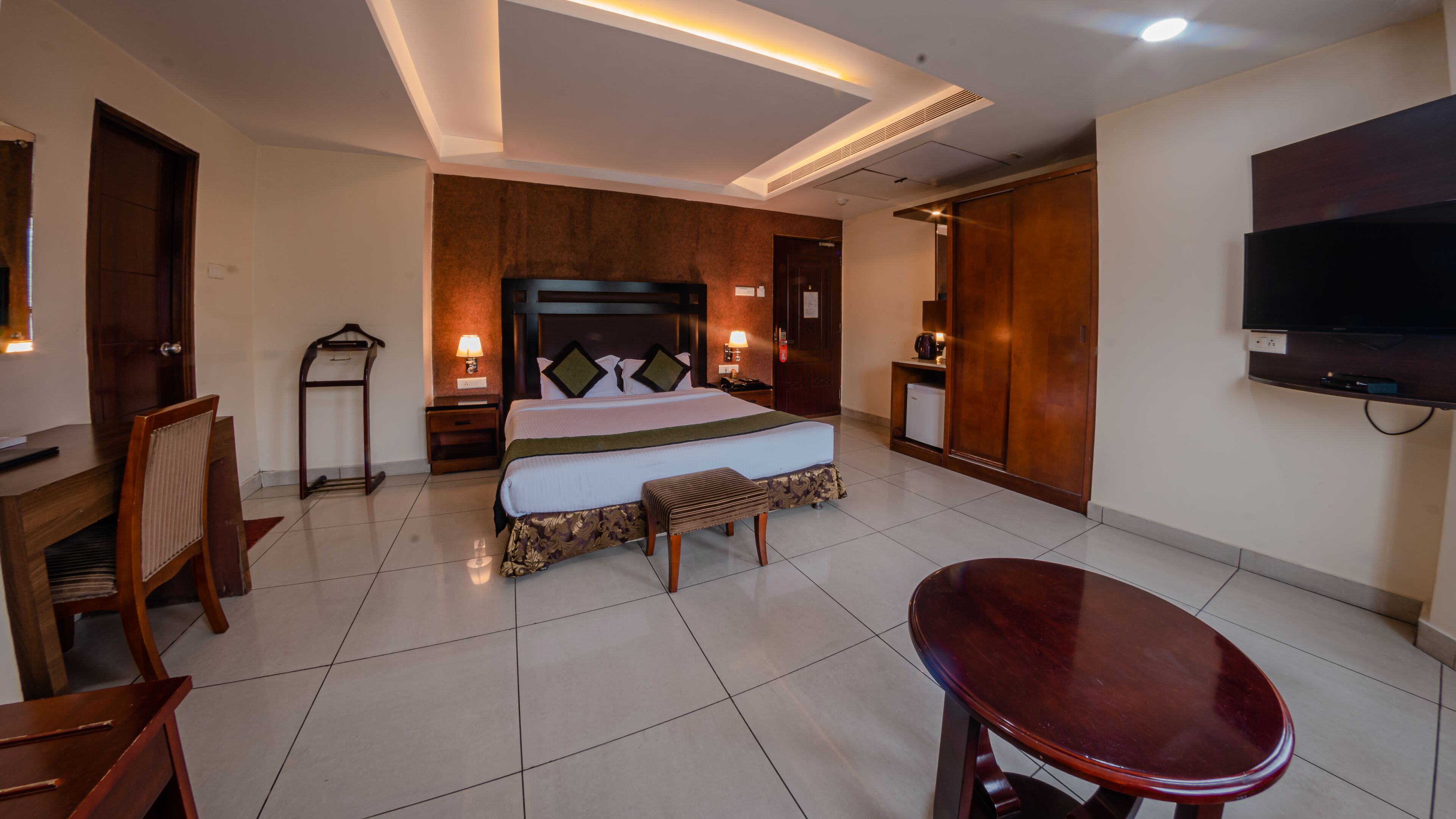Una camera d'albergo con un letto, comodini, una TV, una scrivania e una sedia.