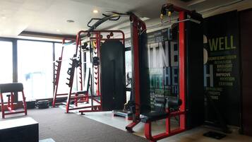 Un gimnasio con varios equipos de ejercicio, incluyendo un rack de sentadillas y bancos de pesas.