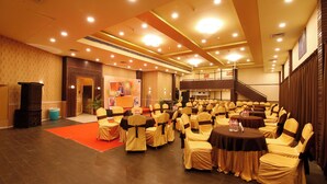 Un salón de banquetes con filas de mesas y sillas, una alfombra roja y una escalera que conduce a un nivel superior.