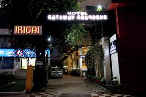 Entrada de un hotel con un letrero de neón que dice 'Hotel Gateway Grandeur' e 'Ikigai'.