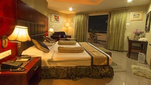 Une chambre d’hôtel avec un lit, des lampes de chevet, un bureau avec un téléphone, une chaise et une vue sur l’extérieur par une fenêtre.