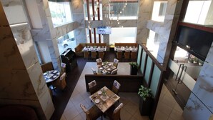 Un restaurante espacioso con techos altos, paredes de mármol y diversas opciones de asientos, incluidas mesas y cabinas.