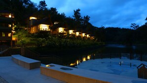 A resort with multiple buildings, a pool, and a bridge over a body of water. - Kofiland Resort (Peermade)