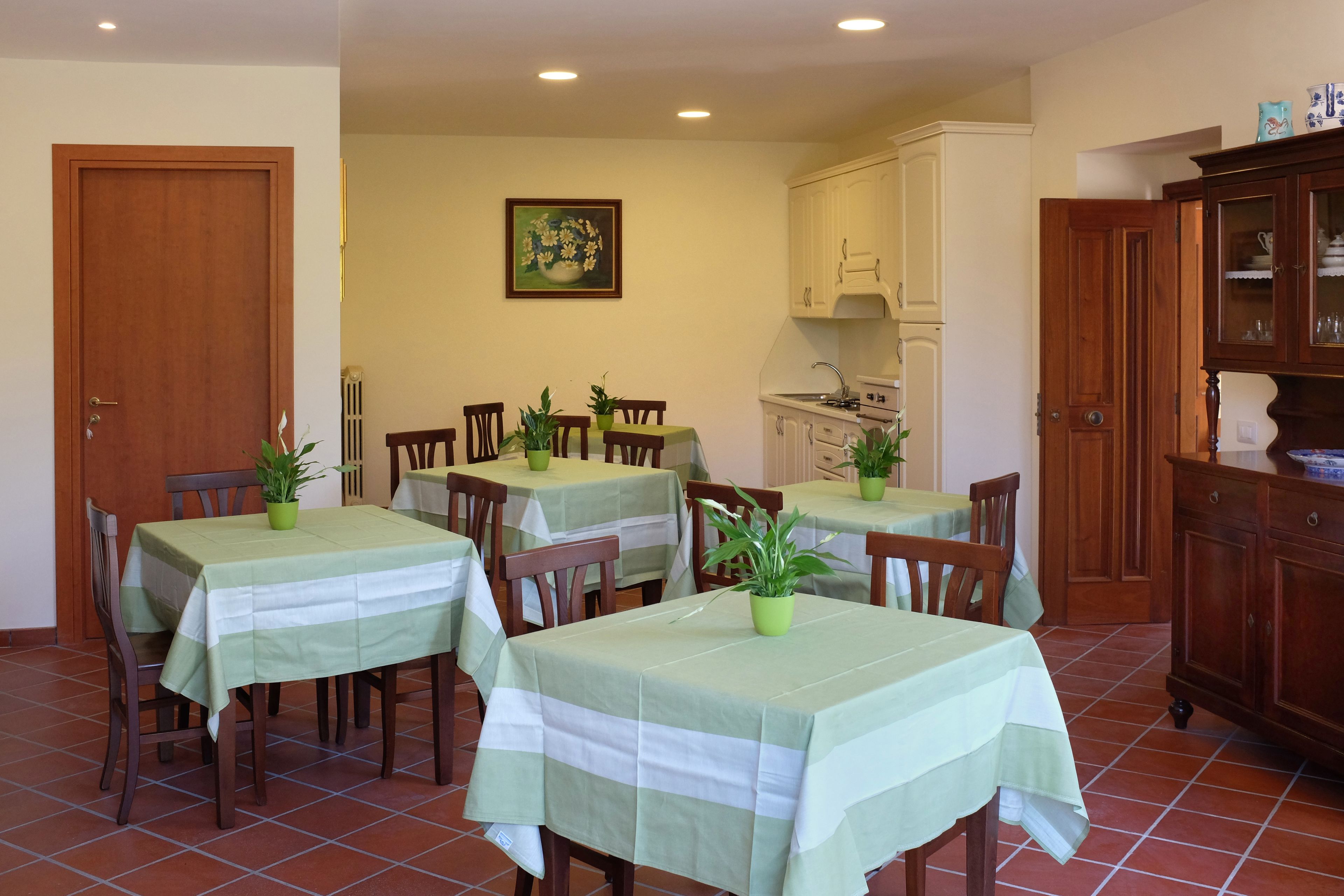 Un comedor con varias mesas, sillas y plantas en macetas.