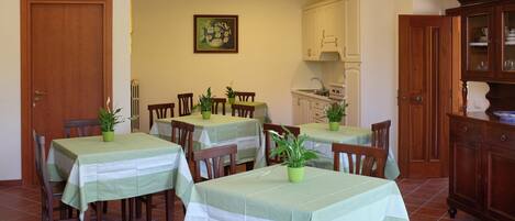 Un comedor con varias mesas, sillas y plantas en macetas.