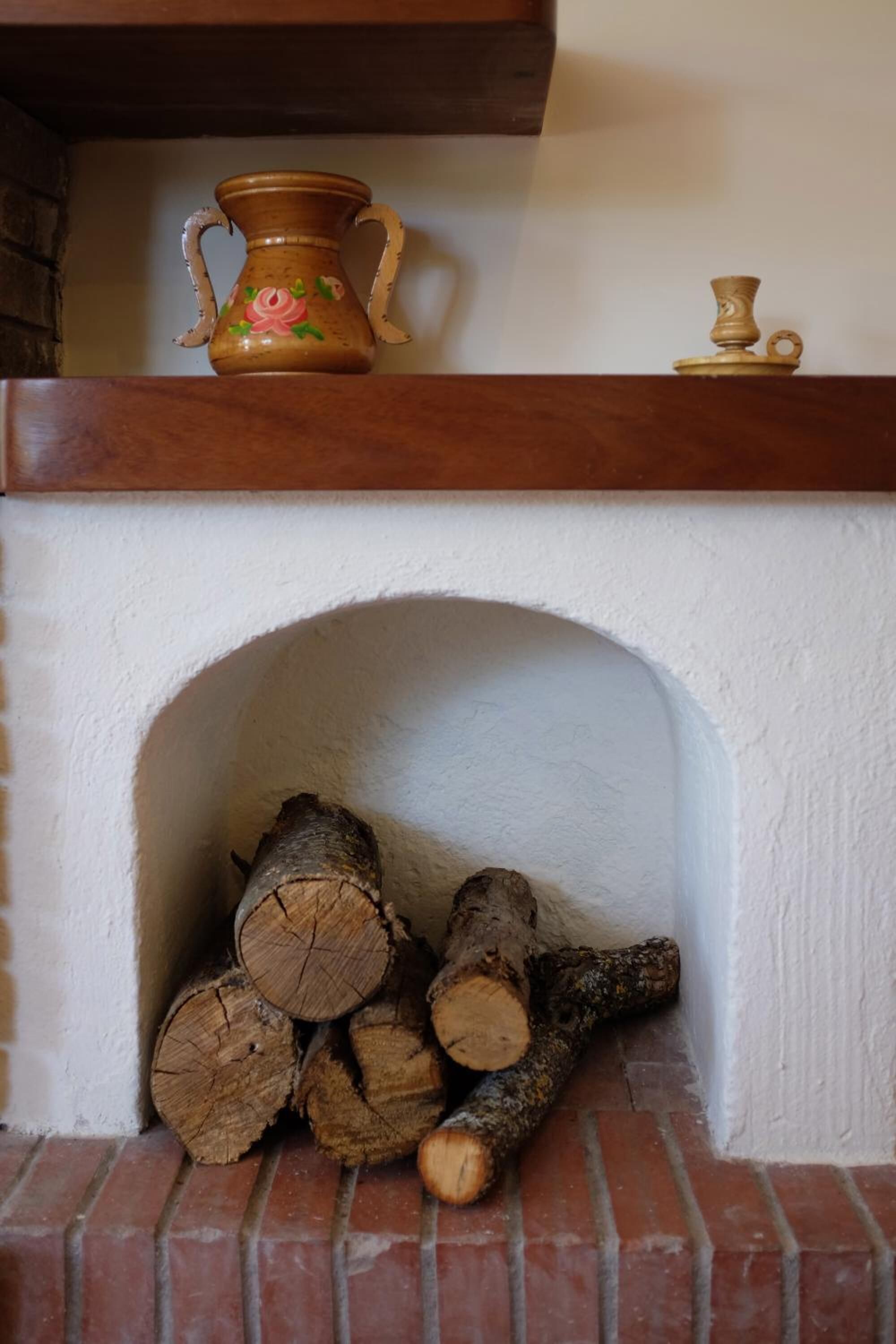 A fireplace with a white mantel, a decorative vase, and a small candle holder.