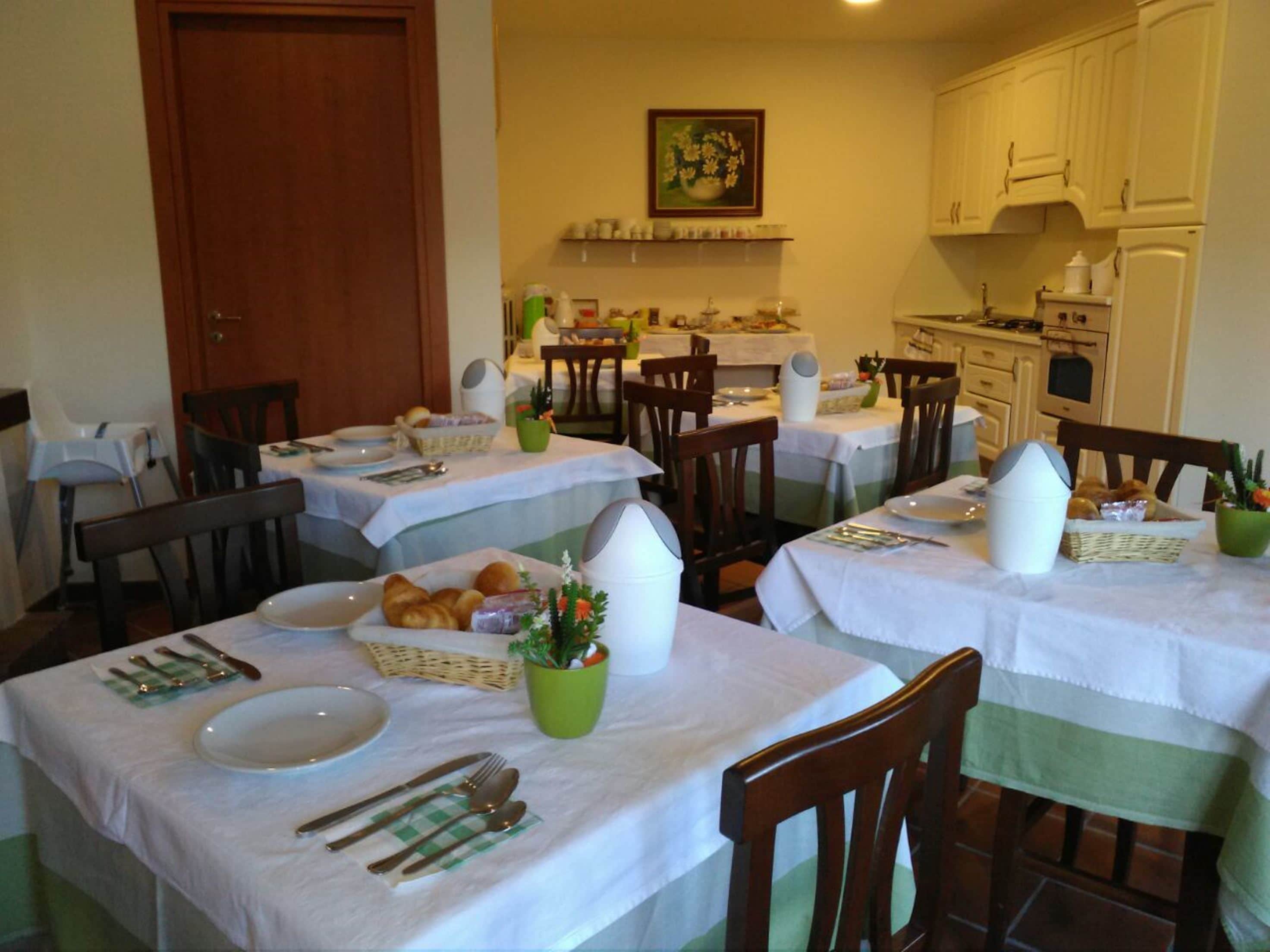 Un'area pranzo con diversi tavoli apparecchiati per la colazione, ognuno con piatti, posate e pane.