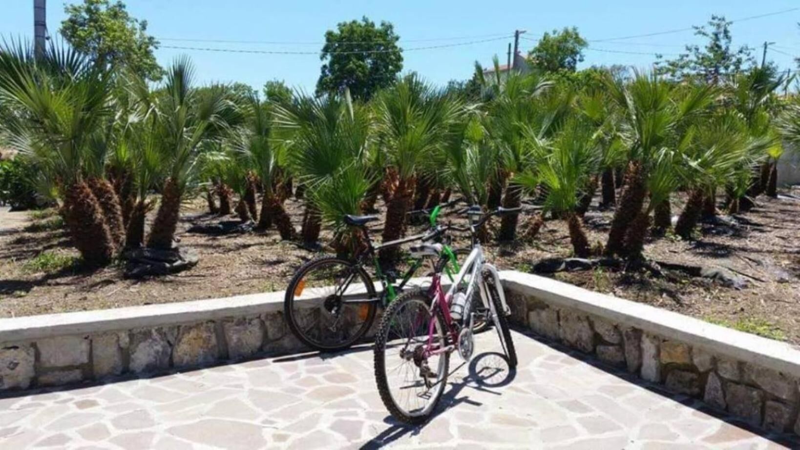 A paved area with a stone wall and two bicycles parked against it.