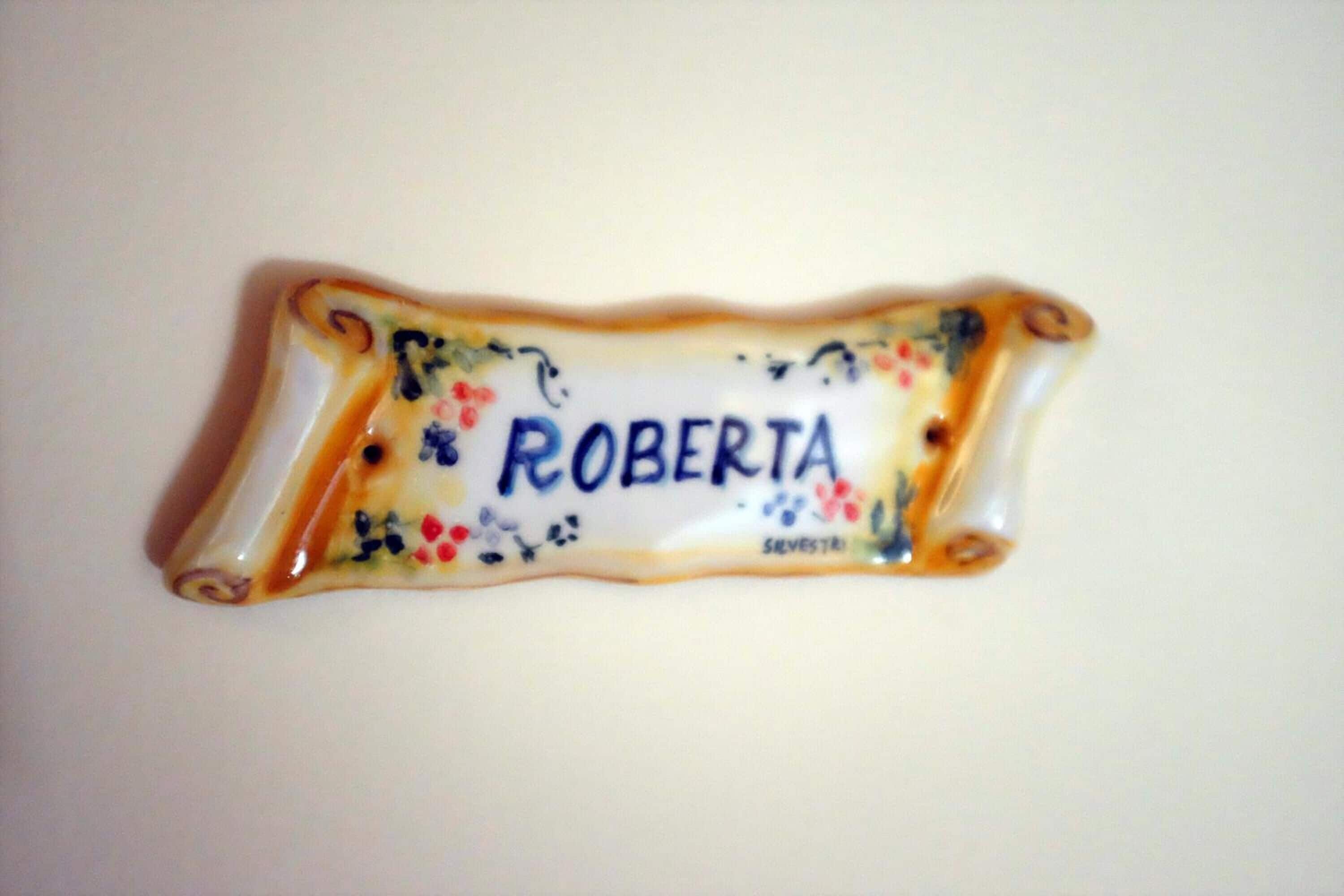 A decorative nameplate with the name "ROBERTA" and floral designs.