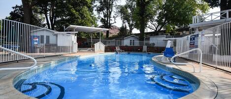 Una piscina con el número 3, rodeada por una cerca blanca, árboles y una zona cubierta.