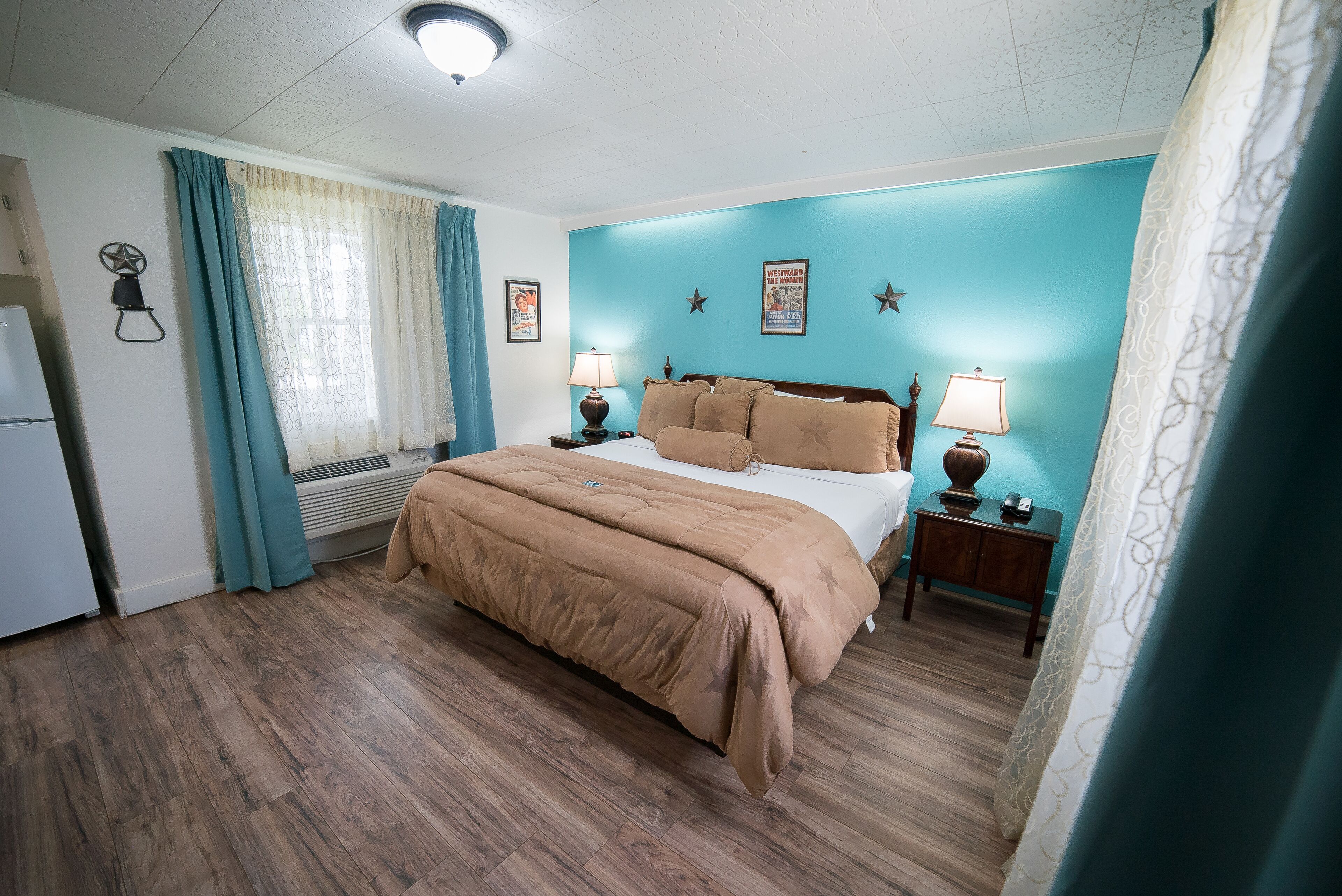 A bedroom with a bed, two bedside tables with lamps, a window with curtains, and a wall with star decorations.