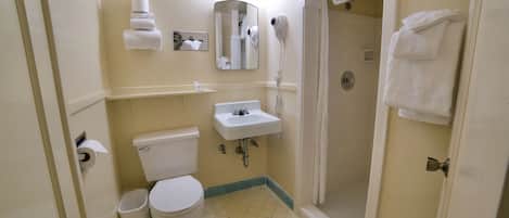 A bathroom with a toilet, sink, mirror, and shower.