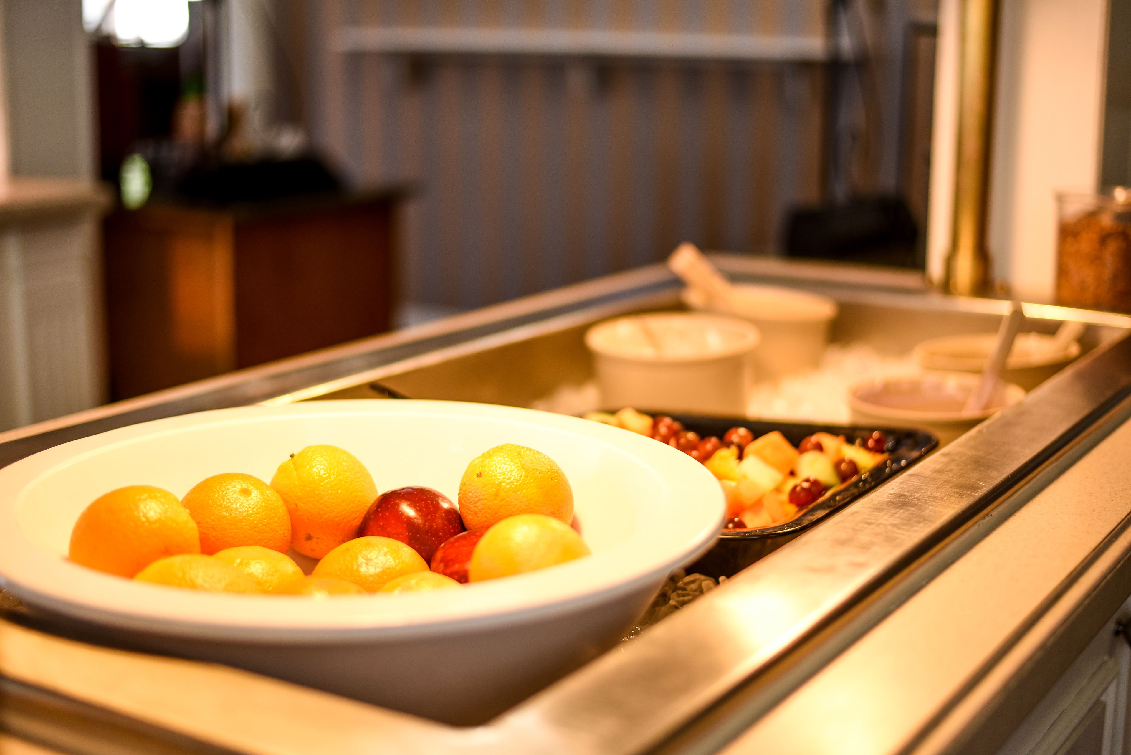A buffet with a bowl of fruit and a tray of assorted items.