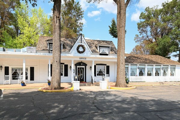 A white building with a black front door and a sign that reads "OFFICE". - Parry Lodge (Kanab)