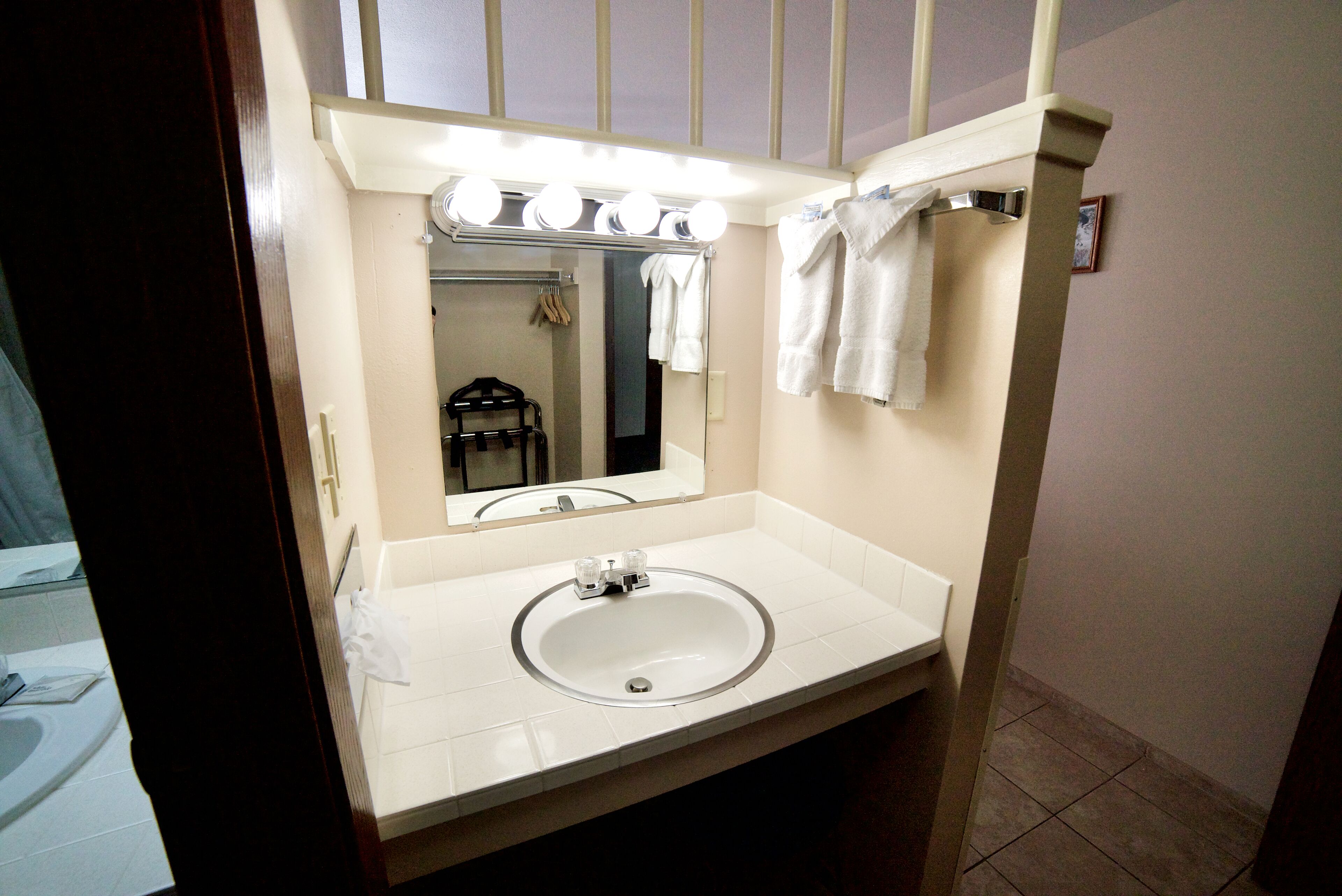Un baño con lavamanos, espejo e iluminación sobre el tocador.