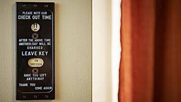 A wall-mounted sign with instructions for check-out time, a reminder to leave the key, and a note to ask if anything is left.