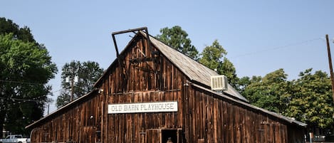 Un granero antiguo con un letrero que dice 'Old Barn Playhouse'.
