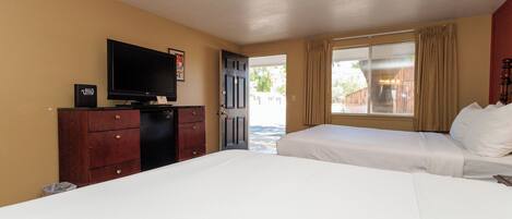 A hotel room with a bed, a TV, a dresser, and a door leading to a balcony.
